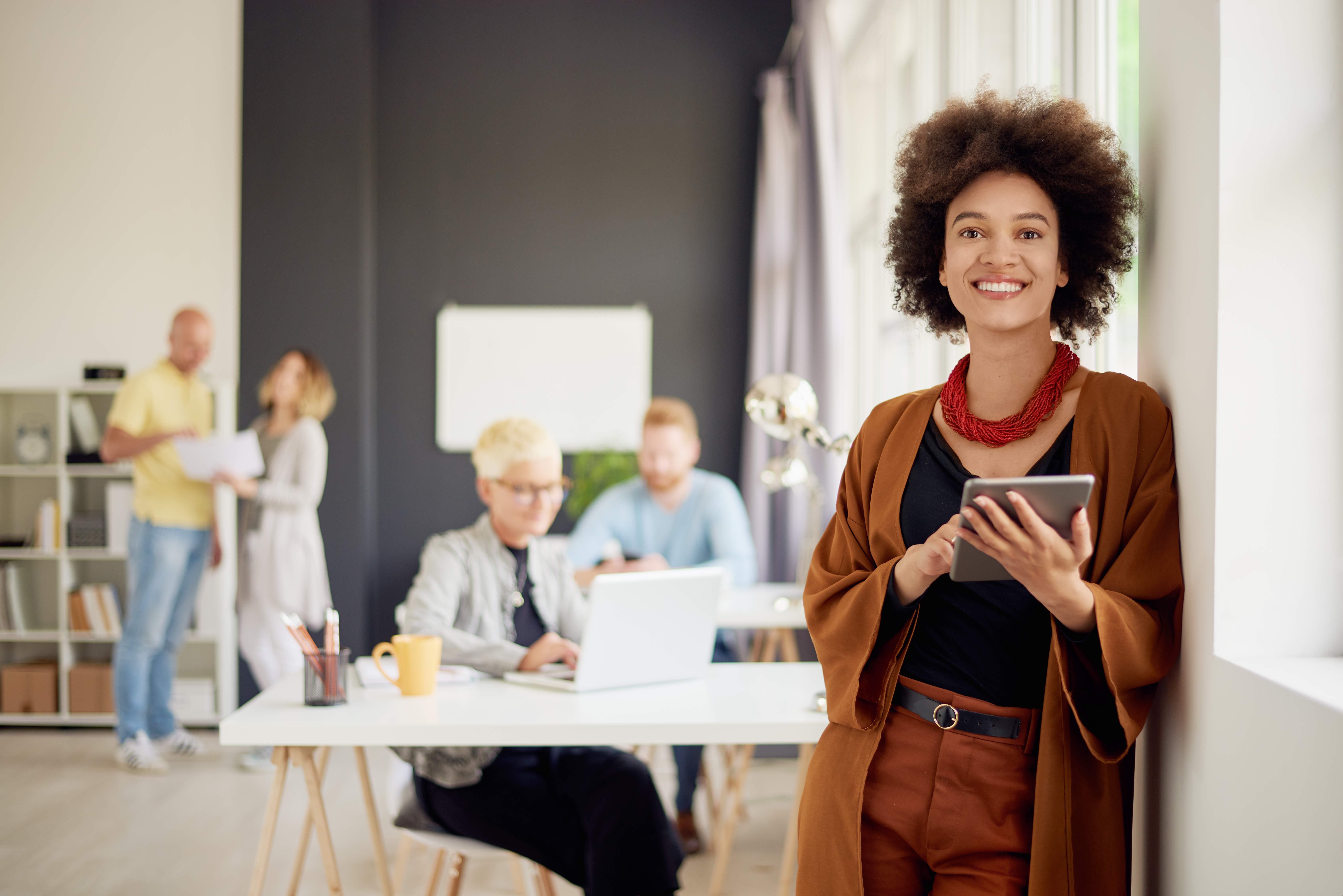 Portrait of young mixed race businesswoman. In background team w Portrait of young mixed race businesswoman. In background team w